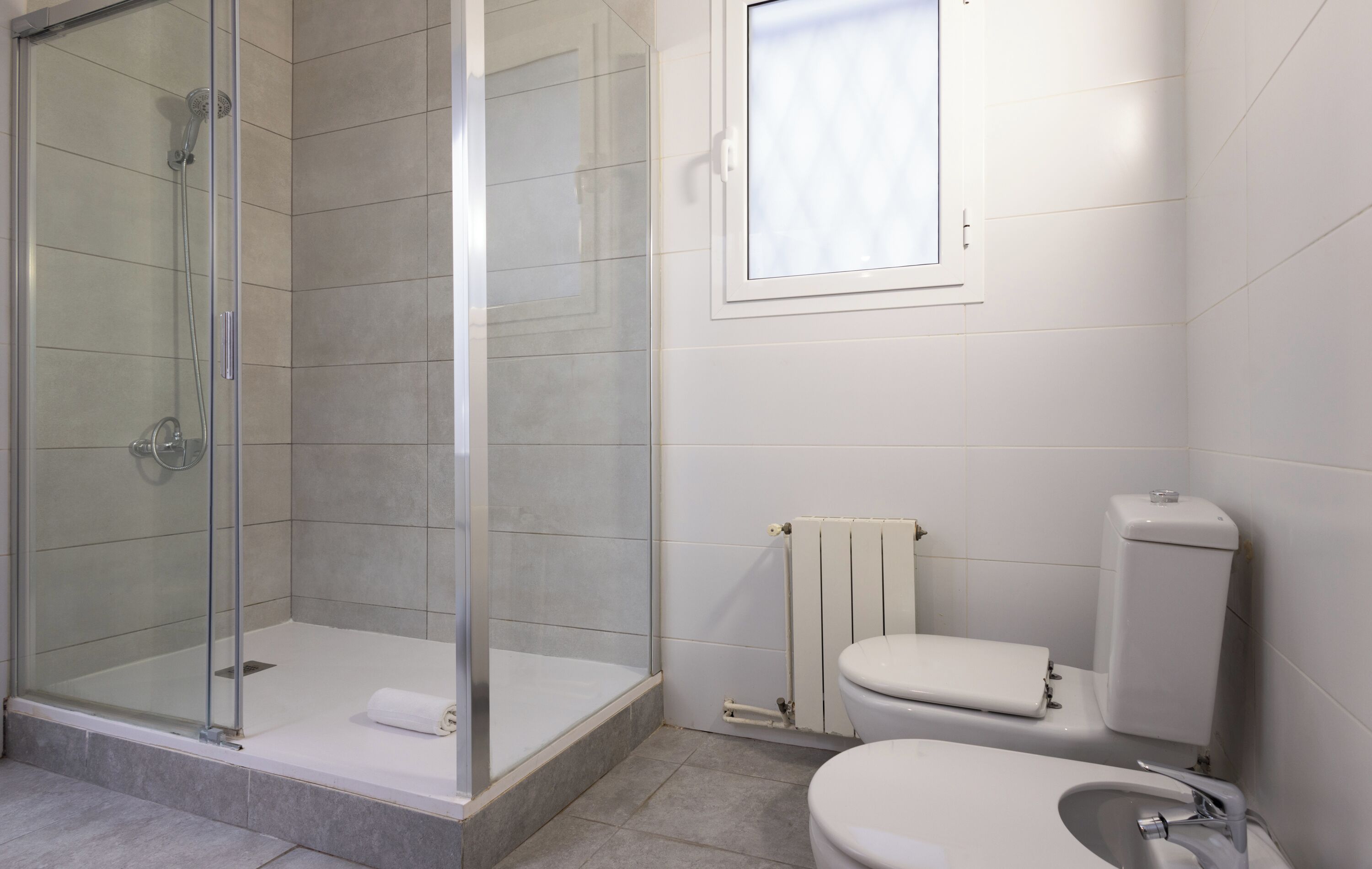 Ein modernes Badezimmer mit einer Glaskabine zur Dusche, einer Toilette und einem Waschbecken.