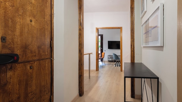A hallway with wooden doors, a black table, and a TV in the background. - Stay U-nique Apartment Gran Via IV (Barcelona)