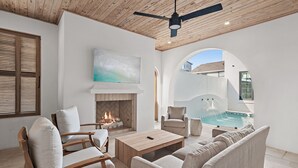Un salon moderne doté d’une cheminée, de sièges confortables et offrant une vue sur une piscine.