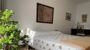 A bedroom with a bed, a potted plant, a desk, and a chair. - MiniLevico (Levico Terme)