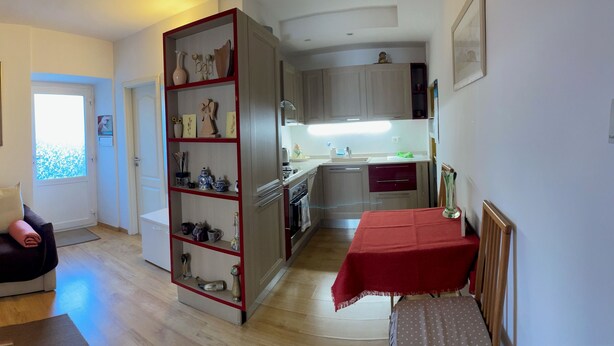 A living room with a sofa, a bookshelf, and a dining area with a table. - MiniLevico (Levico Terme)