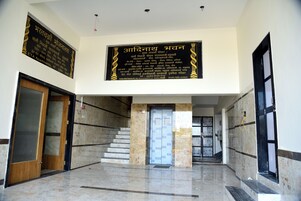 Un vestíbulo con suelo de mármol, una escalera y dos carteles en idioma extranjero.
