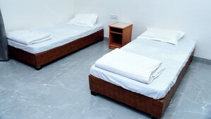 Two single beds with white linens, a wooden nightstand, and a marble floor. - Jainsite (Palitana)