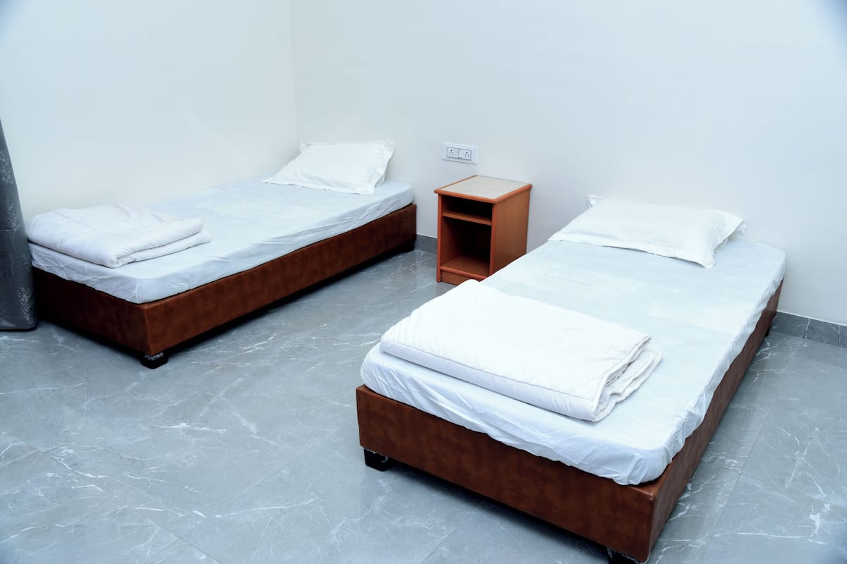 Two single beds with white linens, a wooden nightstand, and a marble floor.