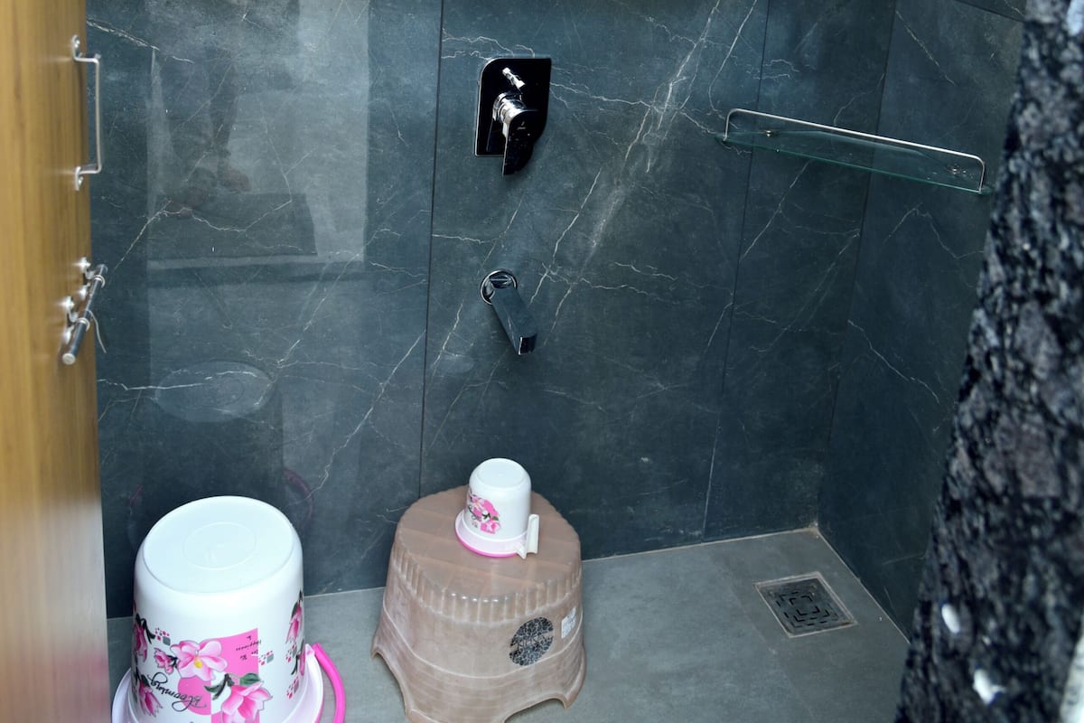 A bathroom with a shower, a toilet, and a small stool.