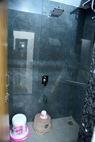 Un baño con ducha, inodoro y un taburete pequeño.