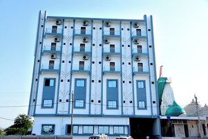 Un edificio de varios pisos con un diseño arquitectónico moderno, con balcones y unidades de aire acondicionado.
