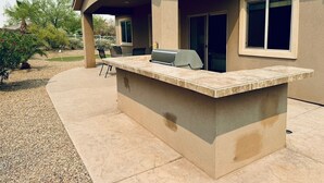 An outdoor kitchen area with a built-in grill and seating.
