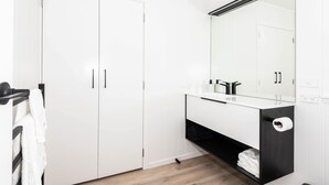 Een moderne badkamer met witte kastjes, een zwart wastafelmeubel en een grote spiegel.