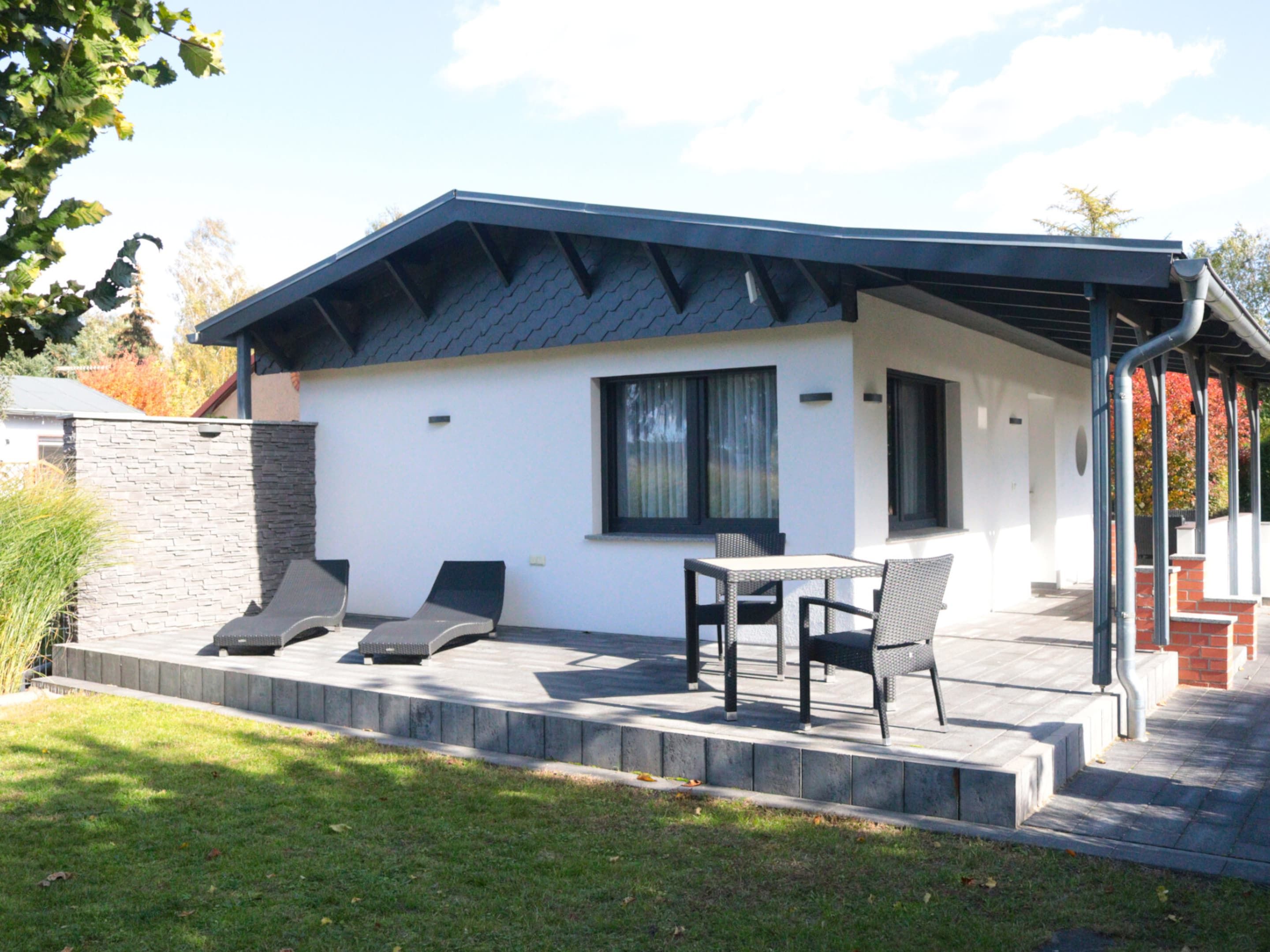 Una casa moderna con un patio, un tavolo e due sedie.