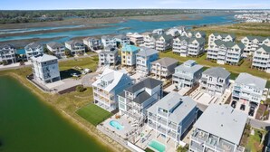 Zona residencial costera con edificios de varios pisos, una piscina y vista al cuerpo de agua.