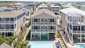 A multi-story hotel with a pool area, outdoor seating, and a view of the ocean. - Turtle by the Sea- 5 bedroom, 5+ bath, w/private pool & elevator, OIB resort. (Ocean Isle Beach)