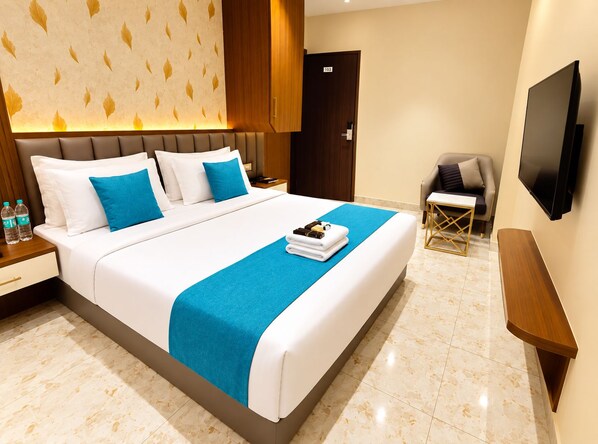 A hotel room with a bed, a desk, a chair, a TV, and a door. - Hotel Indigo (Indore)