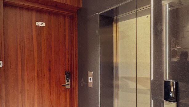 An elevator with a metallic finish and a door with a wooden finish. - Hotel Indigo (Indore)