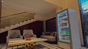 A modern interior with a staircase, a seating area with sofas, a coffee table, and a beverage vending machine. - Hotel Indigo (Indore)