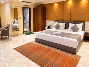 A modern hotel room with a large bed, a sitting area, and a wardrobe. - Hotel Indigo (Indore)