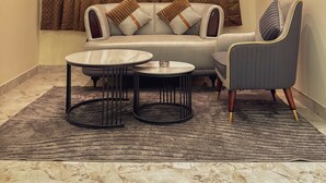 A modern living room with a sofa, armchair, coffee table, and curtains. - Hotel Indigo (Indore)