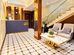 A reception area with a reception desk, a clock, and a staircase leading to upper floors.
