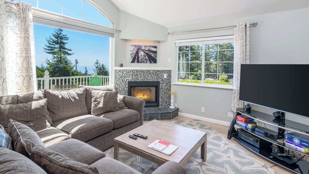 A living room with a fireplace, a sofa, a coffee table, and a TV. - 3 BDR Home in Gualala w/ Ocean Views for 6! (Gualala)