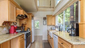 A kitchen with wooden cabinets, granite countertops, a gas stove, a coffee maker, and a dishwasher. - 3 BDR Home in Gualala w/ Ocean Views for 6! (Gualala)