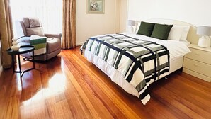 Una habitación de hotel con cama, una silla, una mesita y una mesita de noche.