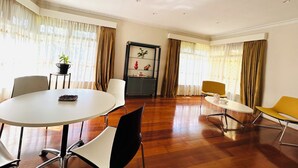 Una habitación amplia con una mesa redonda y sillas, una mesita auxiliar con una planta y un mueble decorativo en la pared.