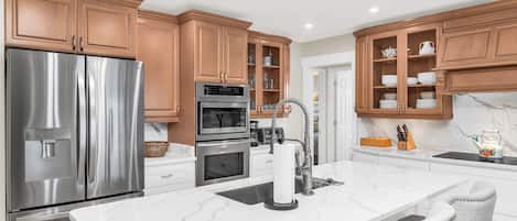 Una cocina moderna con electrodomésticos de acero inoxidable, encimeras de mármol y armarios de madera.
