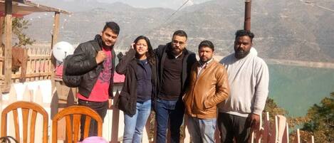 A group of people standing on a wooden deck with a scenic mountain view in the background.