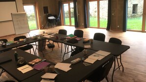 Una sala de conferències amb una taula llarga, cadires, una pissarra i un projector.