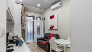 Ein kompakter Wohnraum mit Küchenzeile, Essbereich und einer Couch mit roter Decke.