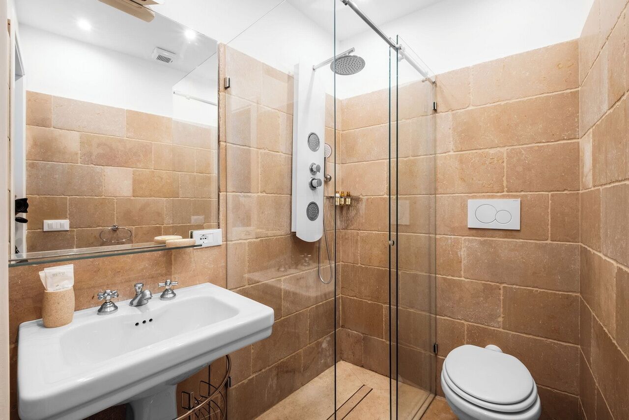 Une salle de bain moderne avec une douche à parois de verre, un lavabo blanc et des toilettes.