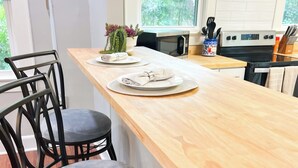 Une cuisine moderne avec un plan de travail en bois, deux tabourets de bar, un four à micro-ondes et une cuisinière.