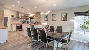 A modern kitchen with a dining area, featuring a central island, built-in appliances, and a large window providing natural light. - Mirage Oasis: Pool & Hot Tub [Free Spa Heating + Early Check-In] (Indio)