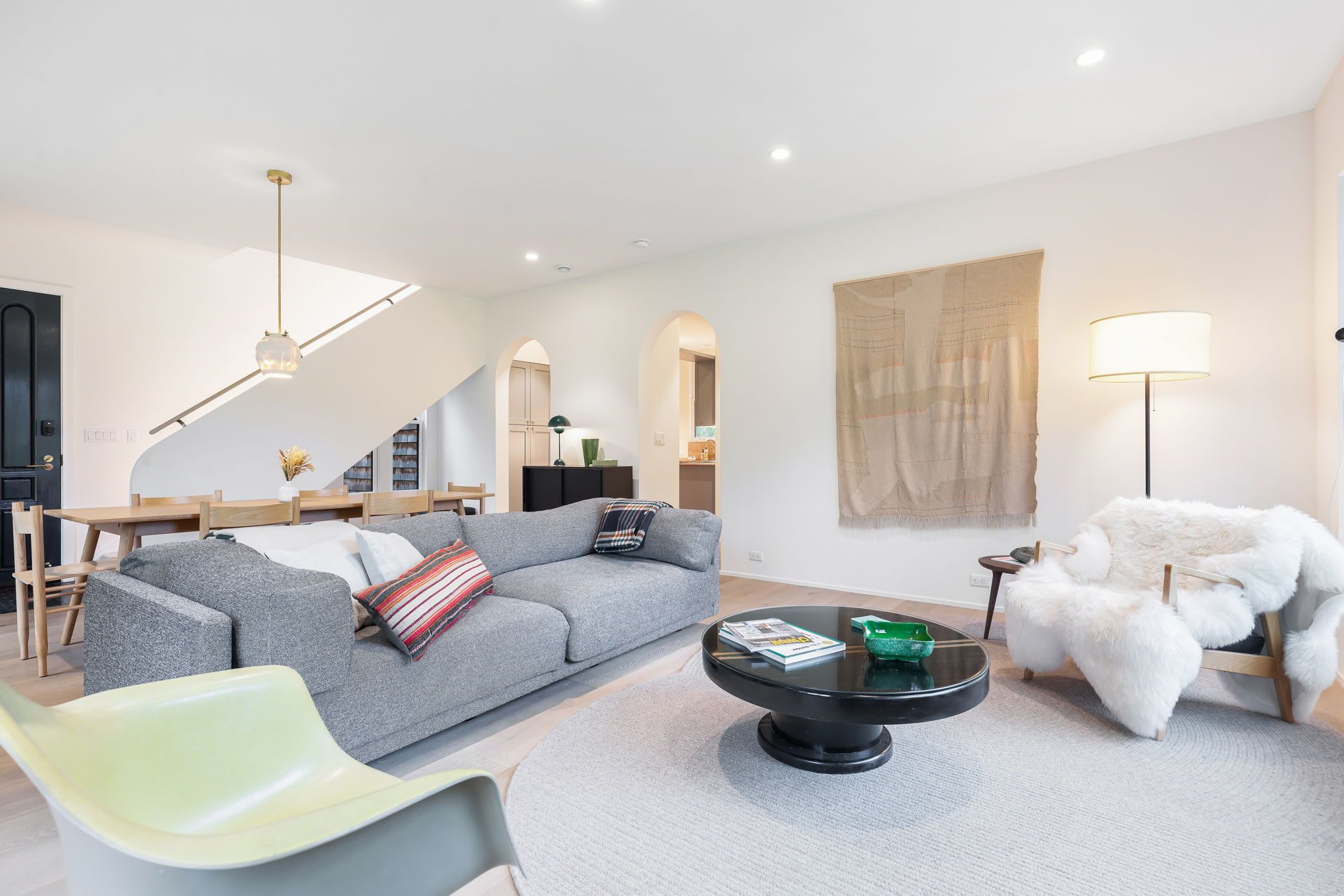 Una sala de estar moderna con un sofá gris, una mesa de centro redonda y un sillón de pelo blanco.