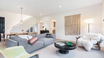 Una sala de estar moderna con un sofá gris, una mesa de centro redonda y un sillón de pelo blanco.