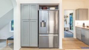 Una cocina moderna con refrigerador de acero inoxidable, armarios grises y encimera de madera.