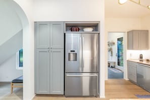 Una cocina moderna con refrigerador de acero inoxidable, armarios grises y encimera de madera.