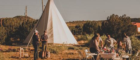 A group of people gathered around a table with a tent in the background.