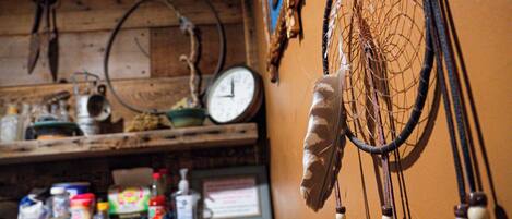 A rustic kitchen with wooden shelves holding various kitchen items and a dreamcatcher hanging on the wall.