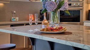A kitchen counter with a plate of food, a bottle of liquor, and a vase of flowers. - Casa Colochos at Los Suenos Resort (Playa Herradura)
