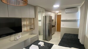 Een hotelkamer met een bed, een televisie, een koelkast en een airconditioning.