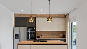 A modern kitchen with a central island, stainless steel appliances, and pendant lighting.