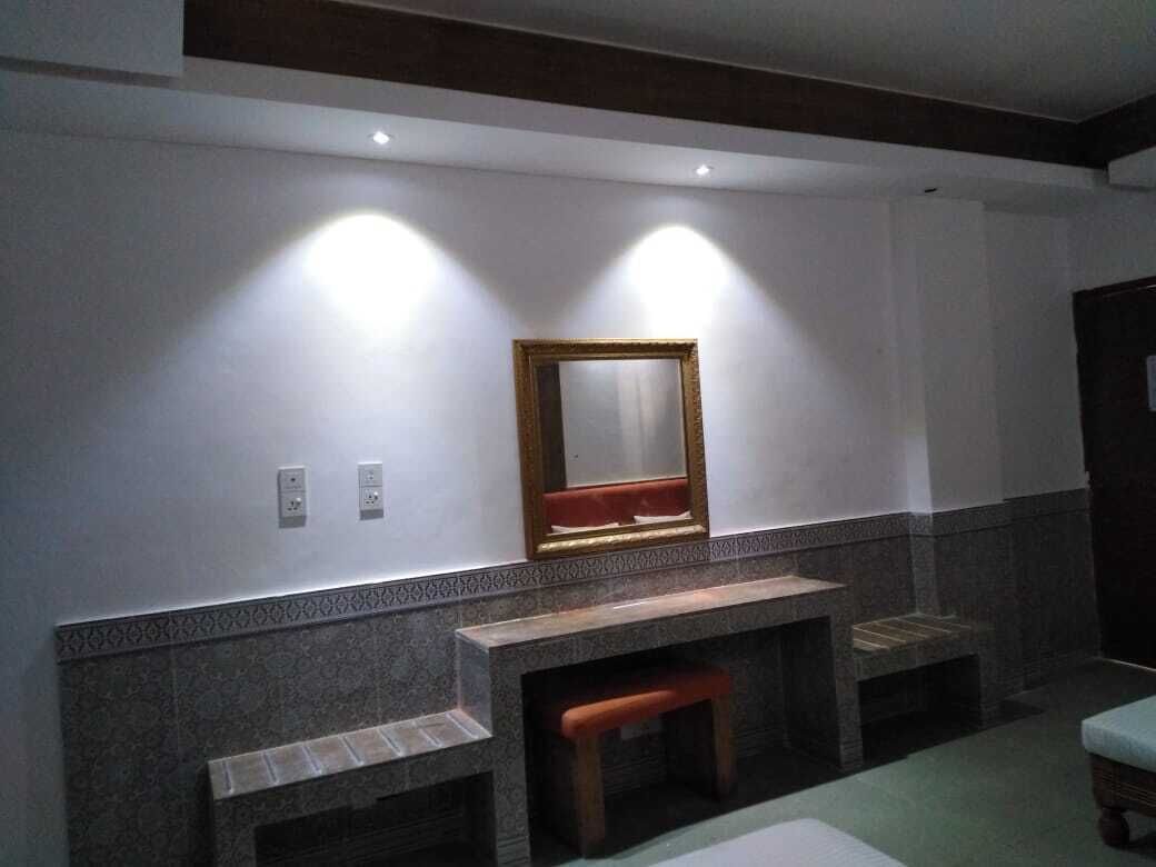 Un baño con pared de mármol, un banco de madera y un espejo.