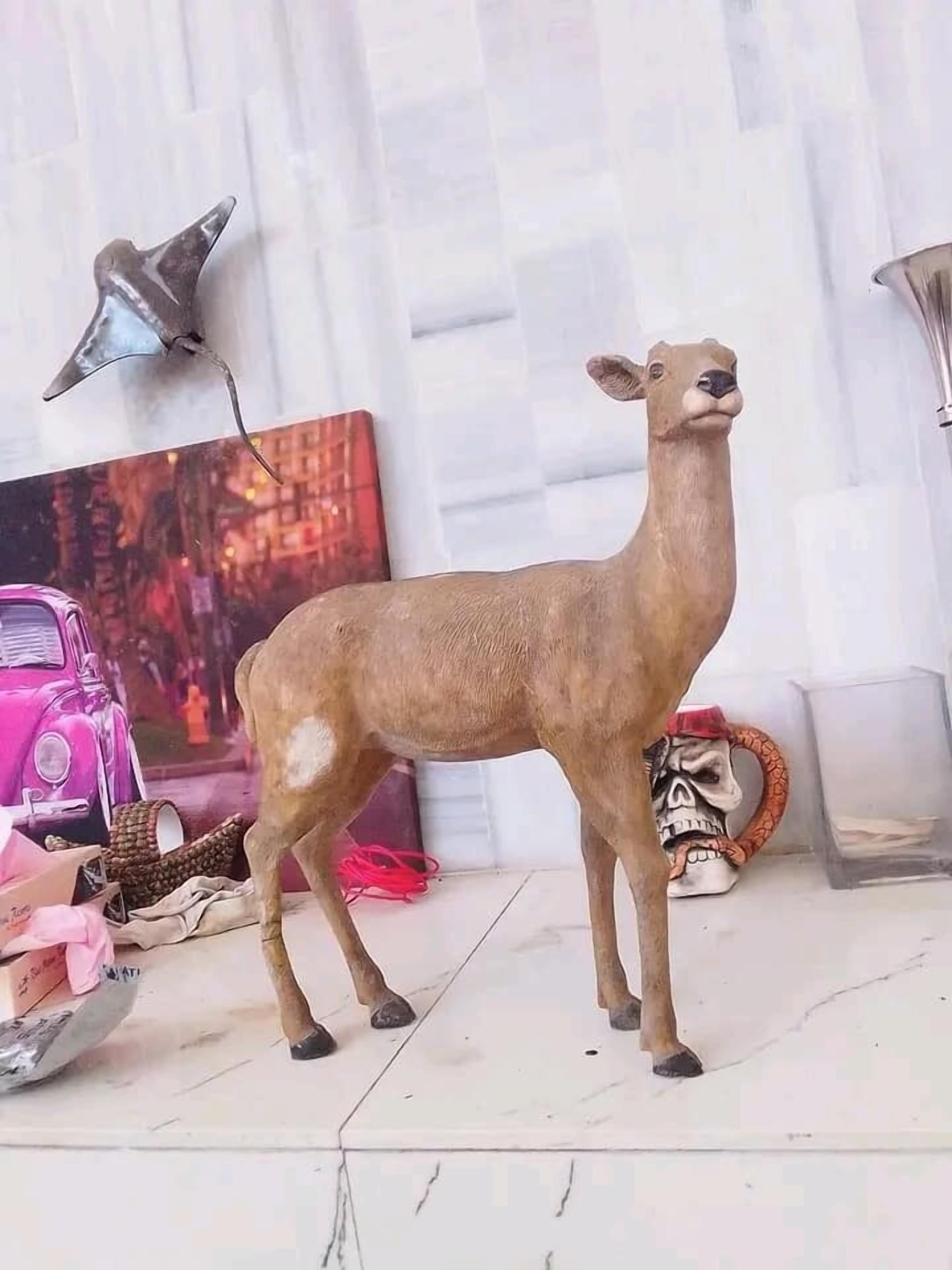 A deer figurine on a tiled floor with a pink car, a skull mug, and a lamp in the background.