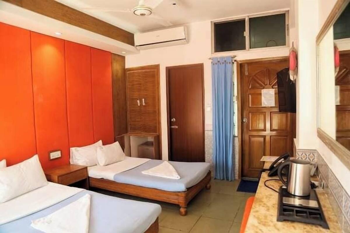Una habitación de hotel con dos camas, kitchenette y un armario de madera.