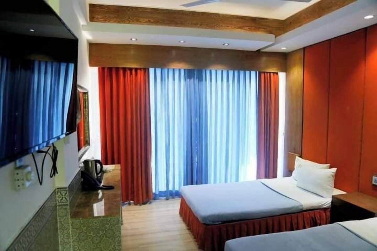 Habitación de hotel con dos camas, televisión y minibar.