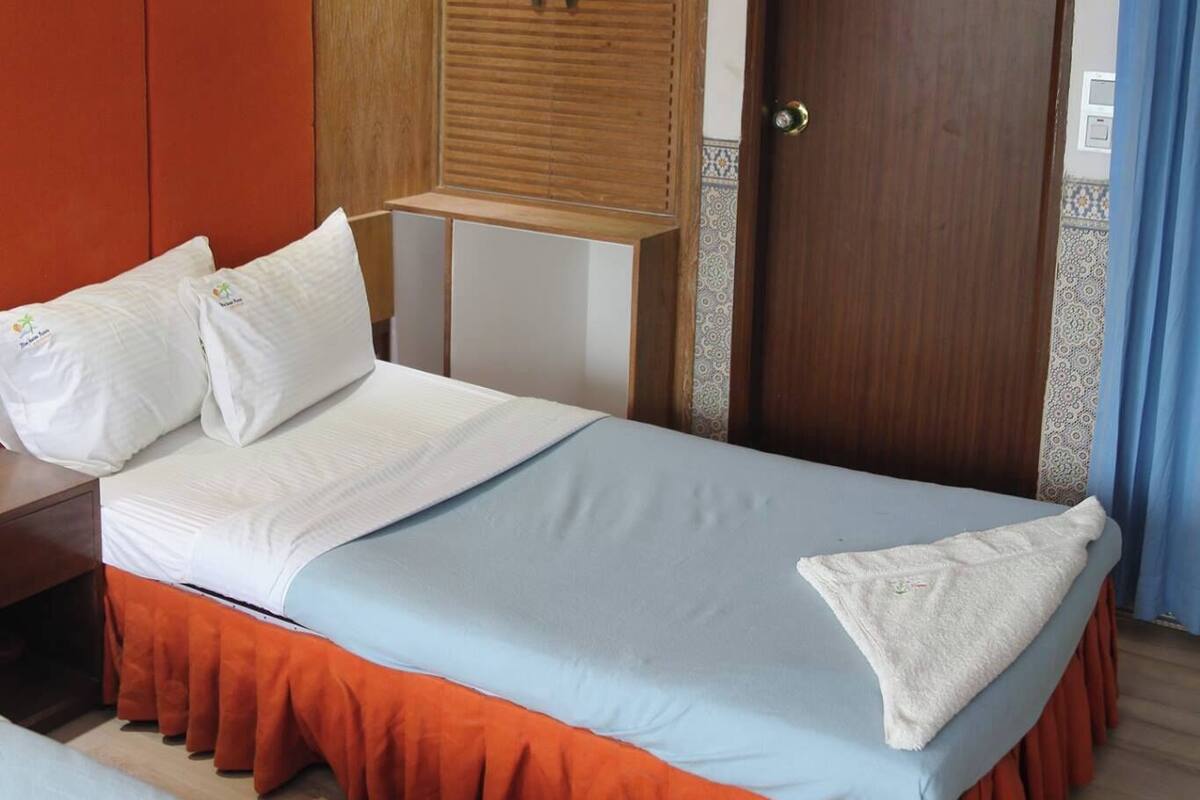 Una habitación de hotel con una cama, un armario, una puerta y un equipo de aire acondicionado.