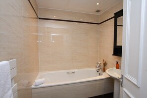 A modern bathroom with a freestanding bathtub, a sink, and a mirror.