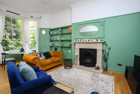 A living room with a fireplace, a sofa, a coffee table, and a bookshelf.