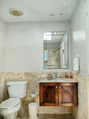 A bathroom with a toilet, sink, and mirror.